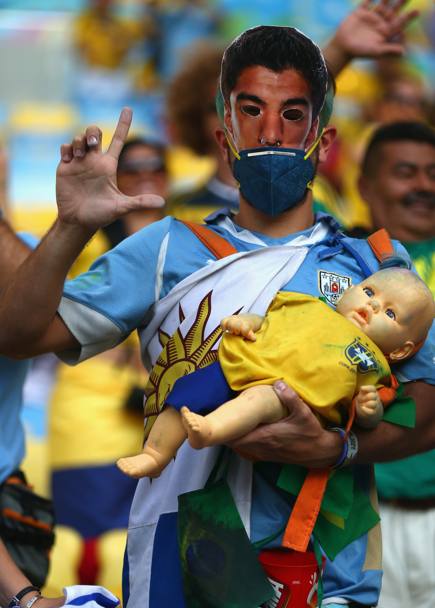 Ironia mal riuscita: maschera di Suarez e un bambino brasiliano tra le braccia. Getty